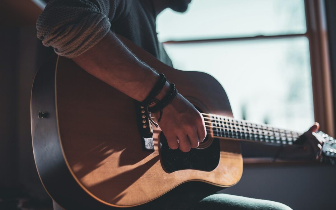 man playing acoustic guitar selective focus photography